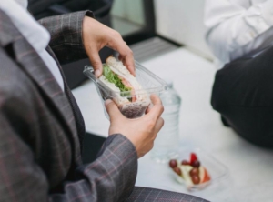 a person eating a sandwich out of plastic food packaging