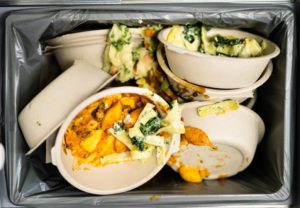 Bowls of wasted food in a trash can. 