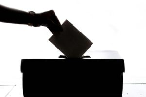 someone putting a vote into a ballet box. Photo by Element5 Digital: https://www.pexels.com/photo/person-dropping-paper-on-box-1550337/