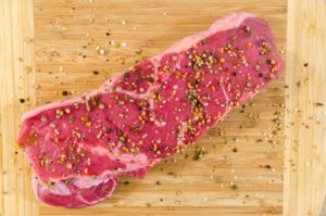 a seasoned cut of meat. Photo by Lukas: https://www.pexels.com/photo/raw-meat-on-beige-wooden-surface-618773/