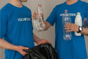 Two people recycling plastic bottles Photo by Mikhail Nilov: https://www.pexels.com/photo/man-in-blue-crew-neck-t-shirt-standing-beside-black-plastic-bag-7475428/
