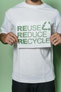 a man holding a sign that says reuse reduce recycle.