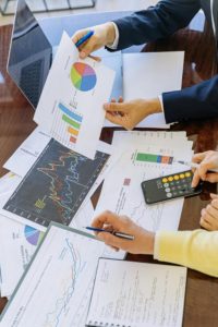A business meeting with graphcs and charts. Photo by Antoni Shkraba Studio: https://www.pexels.com/photo/person-holding-black-smartphone-and-white-printer-paper-5816283/