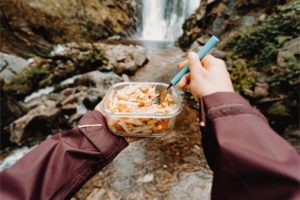 a person eating food out of a container in nature 