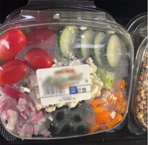 A salad in a plastic package containing condensation. 