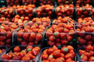 stawberries in plastic packaging. Photo by Elle Hughes: https://www.pexels.com/photo/shallow-focus-photo-of-strawberries-3513237/