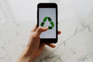 a person holding a phone with a recycling symbol in it. Photo by ready made: https://www.pexels.com/photo/person-holding-black-iphone-3850440/