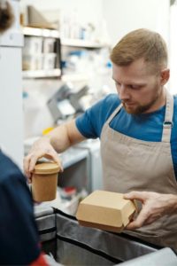 Man putting food in paper packaging into a bag. 