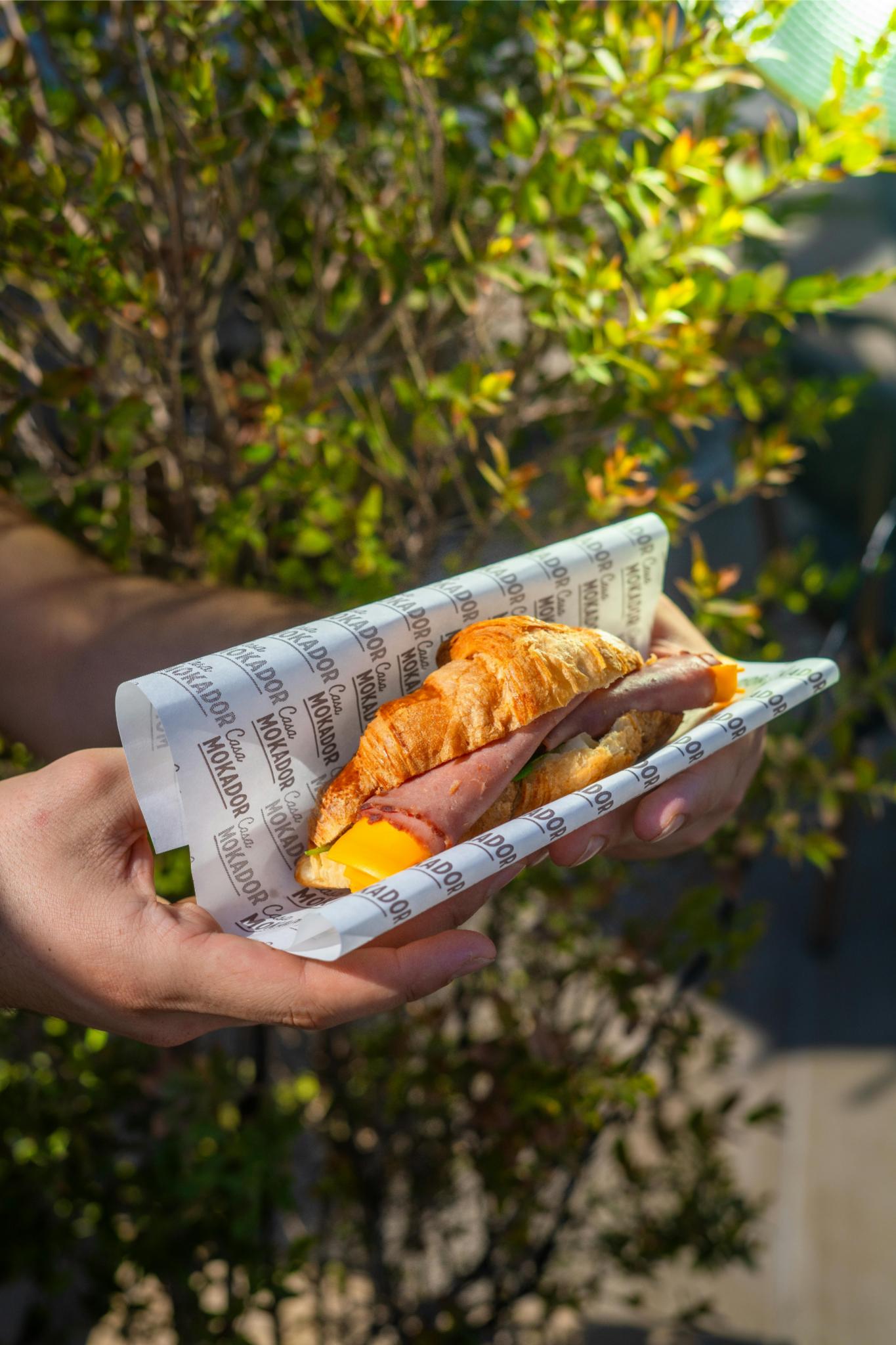 breakfast sandwich Photo by khezez | خزاز: https://www.pexels.com/photo/delicious-croissant-sandwich-in-hands-outdoors-28442301/